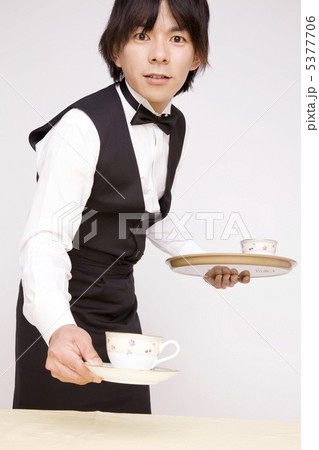 紅茶をテーブルに置くウェイターの写真素材