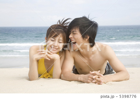 ビーチで寝転がるカップルの写真素材