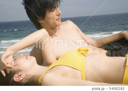 ビーチで寝転がるカップルの写真素材