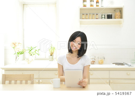 キッチンでタブレットPCを操作する若い女性 5419367