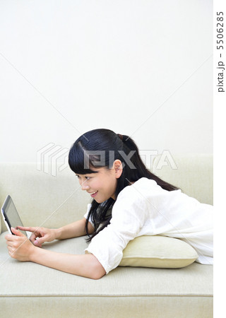 カウチに寝転んでタブレットPCを操作する女性 カウチに寝転んでタブレットPCを操作する女性 5506285