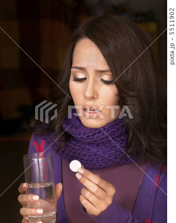 Girl holding glass of water and taking pills. 5511902