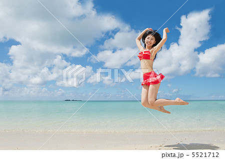 ビーチでジャンプする水着の女性の写真素材