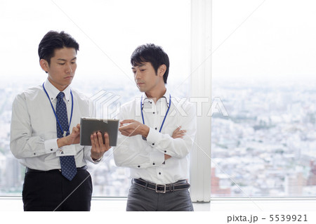 モバイルタブレット片手に会話するビジネスマン モバイルタブレット片手に会話するビジネスマン 5539921