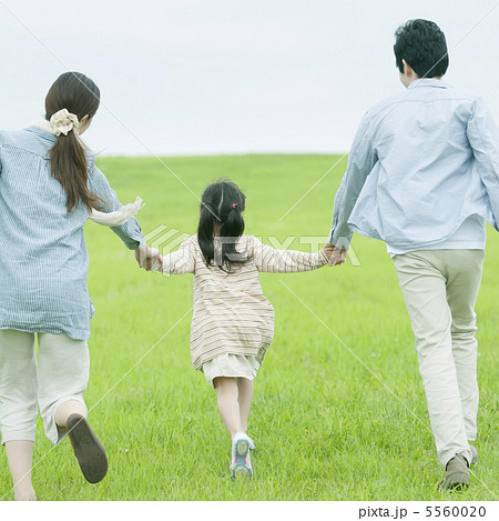 草原で手をつなぐ親子の後姿の写真素材