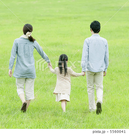 草原で手をつなぐ親子の後姿の写真素材