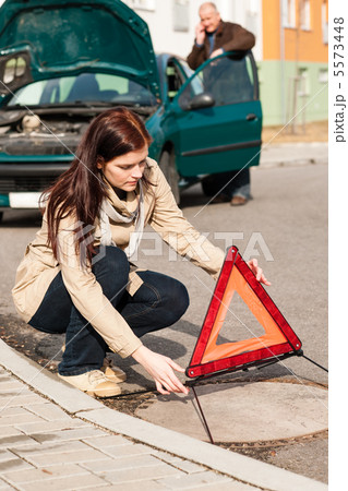 Woman putting triangle sign for car breakdown Woman putting triangle sign for car breakdown 5573448