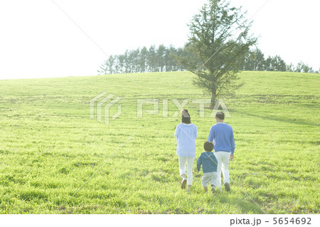 草原を歩く親子３人の後姿 5654692