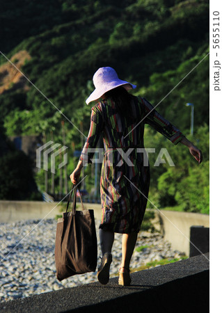 防波堤を歩く女性の写真素材