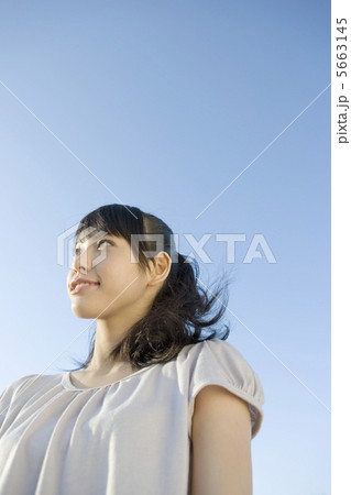 青空の下に立つ20代女性 5663145