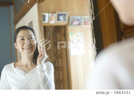化粧台の鏡に映る化粧をする50代女性 5663331
