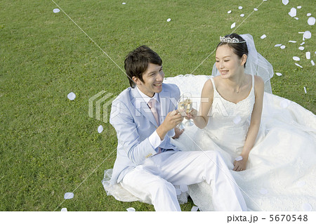 野原に座り乾杯する新郎新婦 5670548