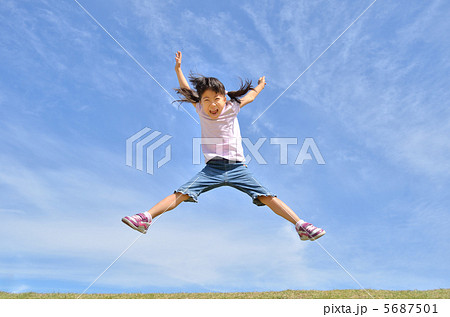 青空でジャンプする女の子の写真素材