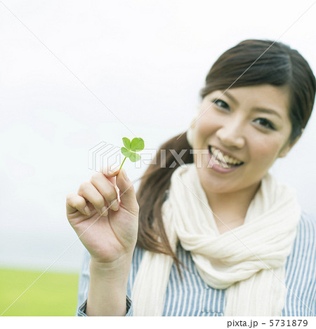 草原で四葉のクローバーを持ち微笑む女性 5731879