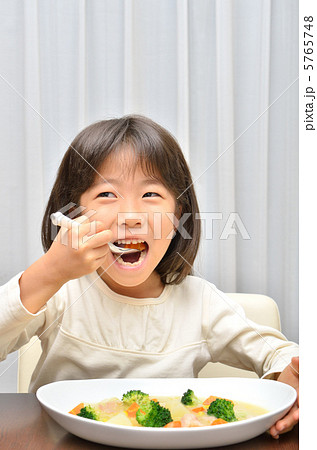 クリームシチューを美味しそうに食べる女の子の写真素材