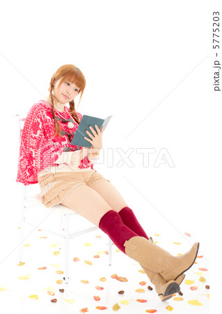 たくさんの落ち葉の中で椅子に座って本を読む女の子 5775203