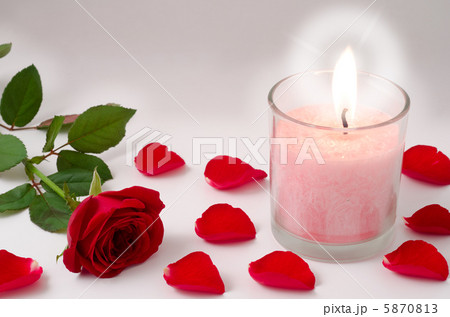 ロウソクと赤いバラの花と花びらの写真素材