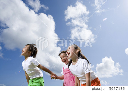 青空を背に並んで叫ぶ子供三人 5957136
