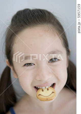 クッキーをくわえる笑顔の女の子の顔アップ 5957159