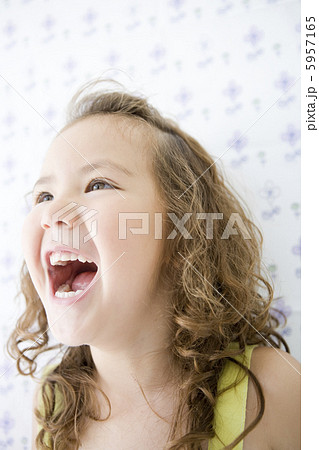 大きく口を開ける女の子の顔アップの写真素材