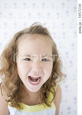 大きく口を開ける女の子の顔アップの写真素材