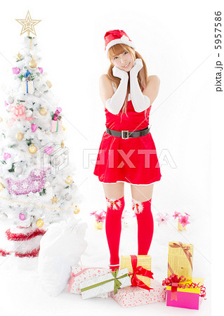クリスマスツリーの横でたくさんのプレゼントに囲まれたキュートなサンタガール 5957586
