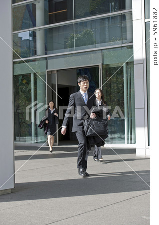 オフィスビルから外に出るビジネスマンたち 5961882