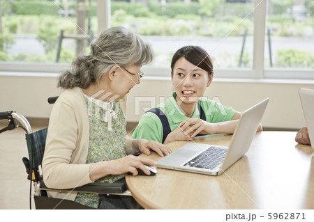 介護施設でパソコンを使うシニア女性と介護士 5962871