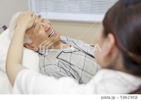 ベッドの男性と笑顔で会話する女性介護士 ベッドの男性と笑顔で会話する女性介護士 5962908