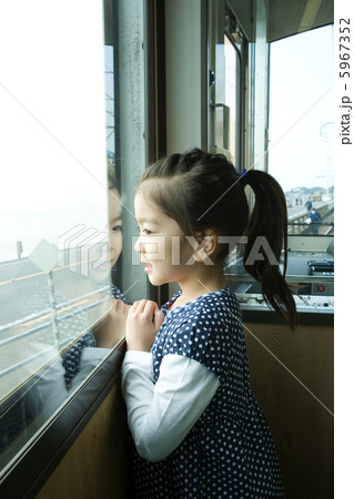 電車の窓から景色を眺める6歳女の子の写真素材