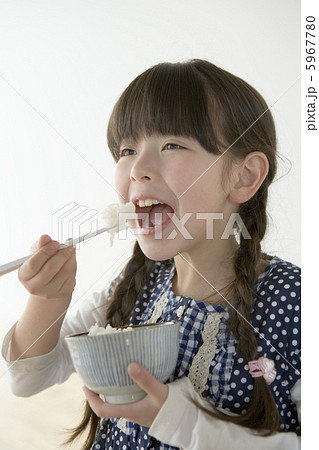 8歳女の子がご飯を口に入れる瞬間の写真素材