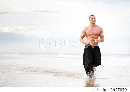 Young man running along a beach 5967859