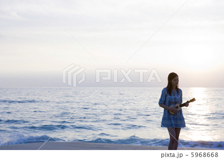 海岸でギターを弾く若い女性 5968668
