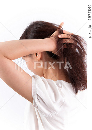 髪をかきあげる若い女性の後ろ姿の写真素材