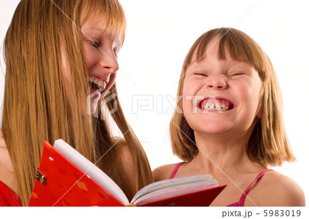 Two little girls looking like sisters holding red book, laughing Two little girls looking like sisters holding red book, laughing 5983019