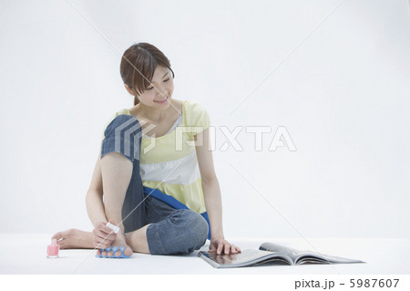 ペディキュアを塗りながら雑誌を読む20代女性 5987607
