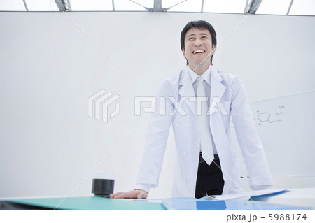 机に手をつき立つ白衣の40代男性 5988174