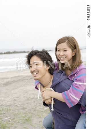 海辺でおんぶする代男女の写真素材