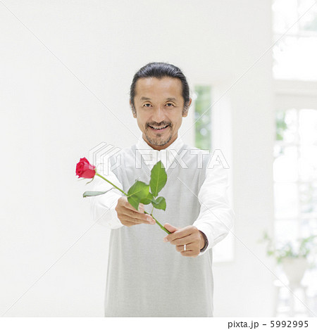 バラの花を差し出す中高年男性の写真素材