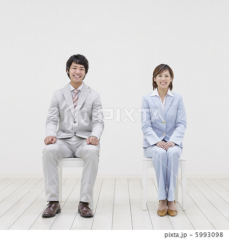 椅子に座るスーツ姿の男女の写真素材