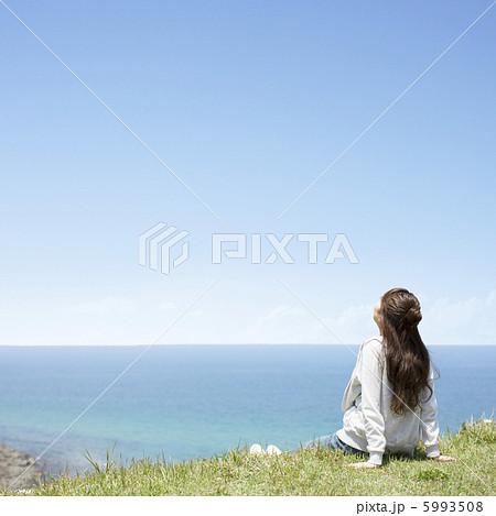 海の前で空を見上げる女性の写真素材