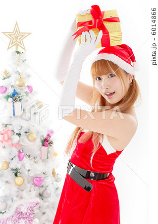 クリスマスツリーと陽気にプレゼントを掲げるセクシーな女性サンタ 6014866