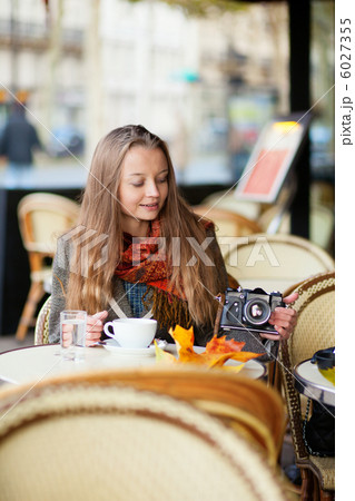 Beautiful young woman in a cafe holding an old-fashioned photo c 6027355