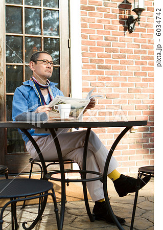 カフェで新聞を読むシニア男性の写真素材