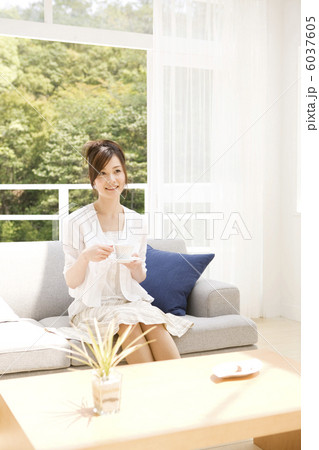 ソファに座ってティーを飲もうとする女性 6037605