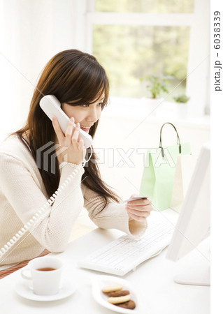 クレジットカードを見ながら電話する女性 6038339