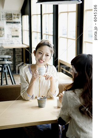 カフェで話し合う女子大生達の写真素材