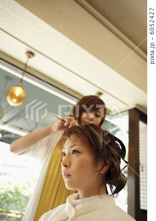 パーマ液を髪に塗布される女性 6052427