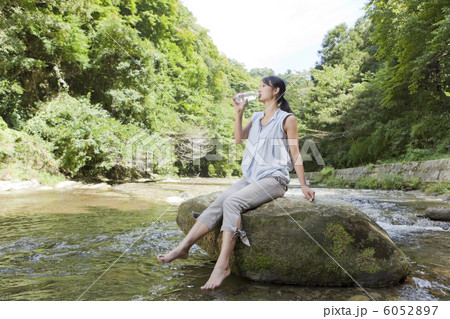 渓流の岩に腰掛けて水を飲む女性 6052897