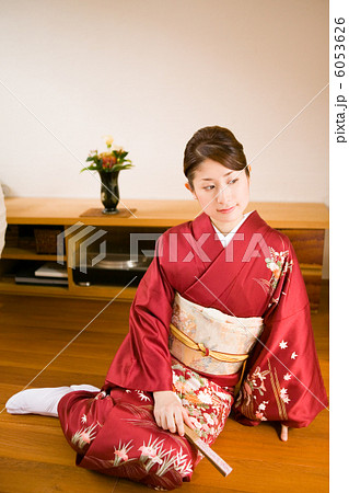 フローリングの床に座る着物姿の若い女性の写真素材